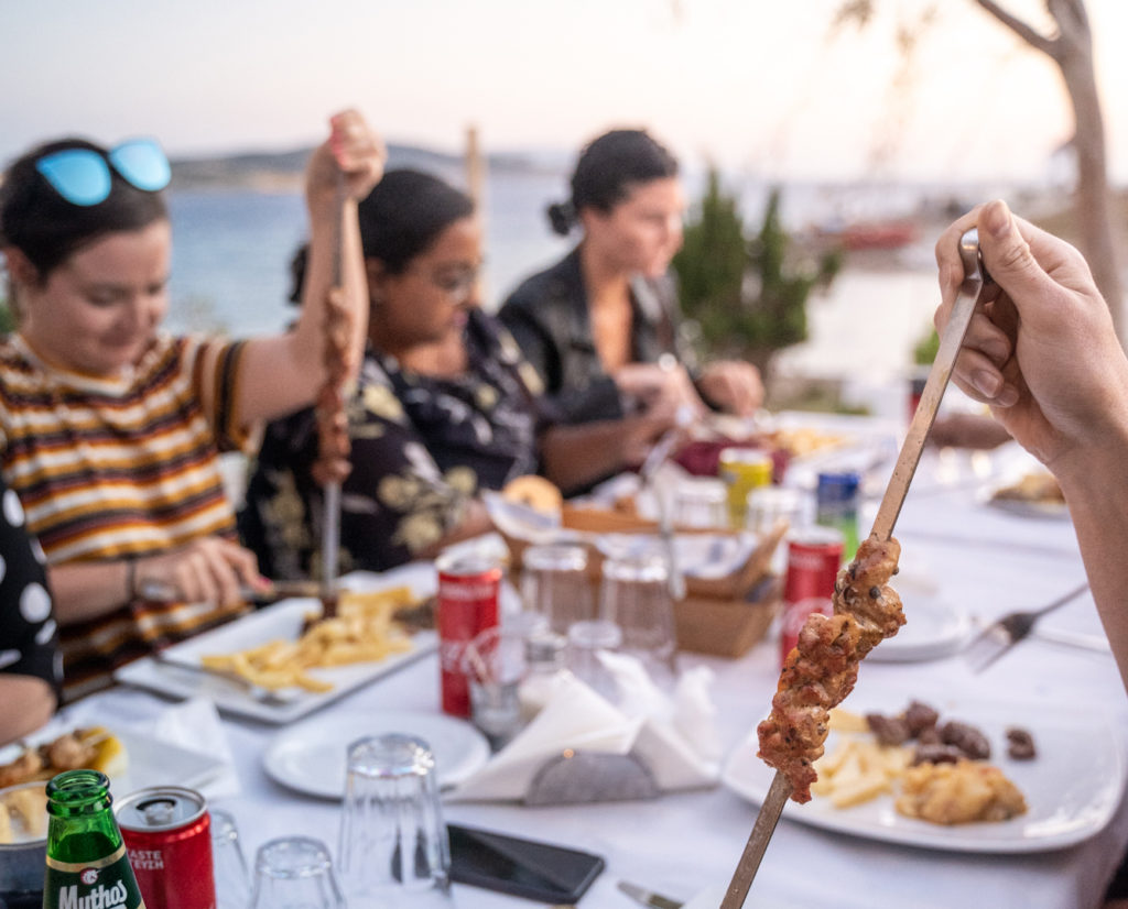 group of young women eating Greek food, including souvlaki