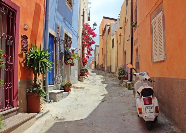 an Italian street with colourful houses and a scooter
