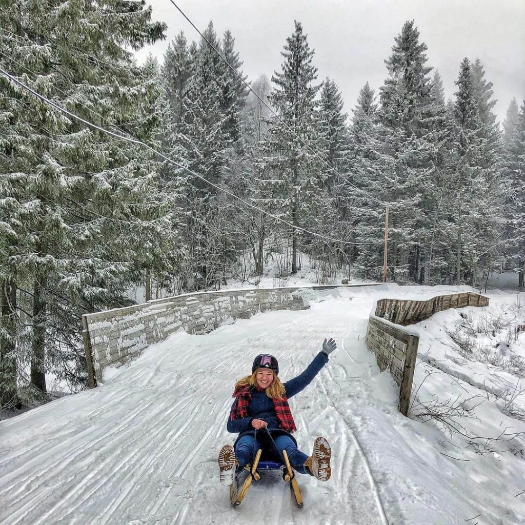 Young woman sledding across a snowy bridge.