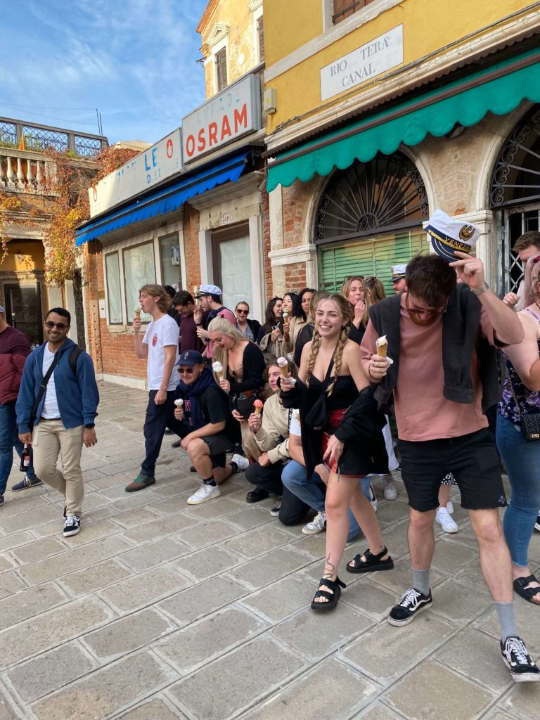 Candid image of group of young travellers eating ice cream on an Italian street.