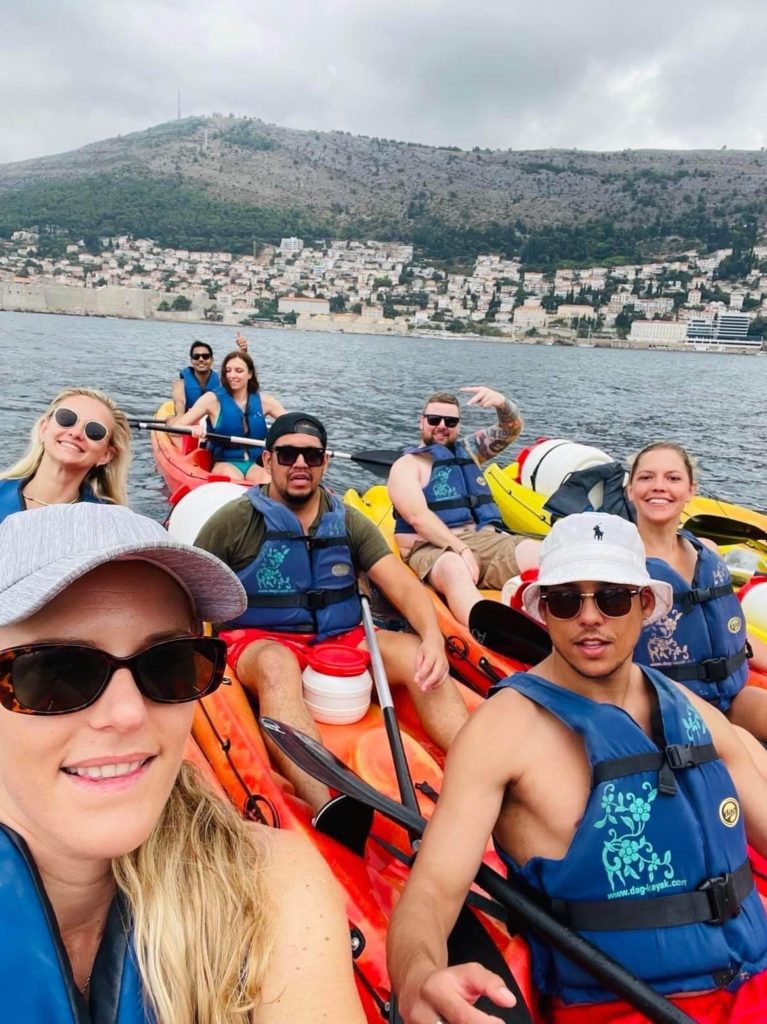 group of young travellers kayaking in Croatian waters. All are wearing blue life jackets.
