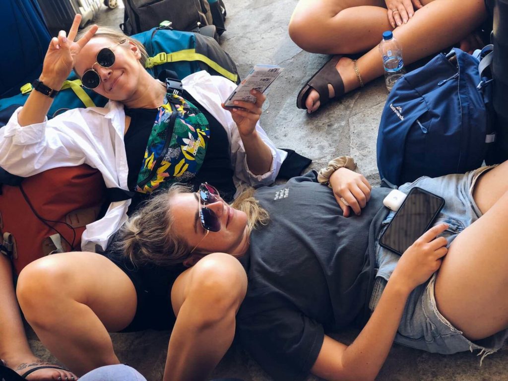 two women lounging on the floor wearing sunglasses and summer clothes