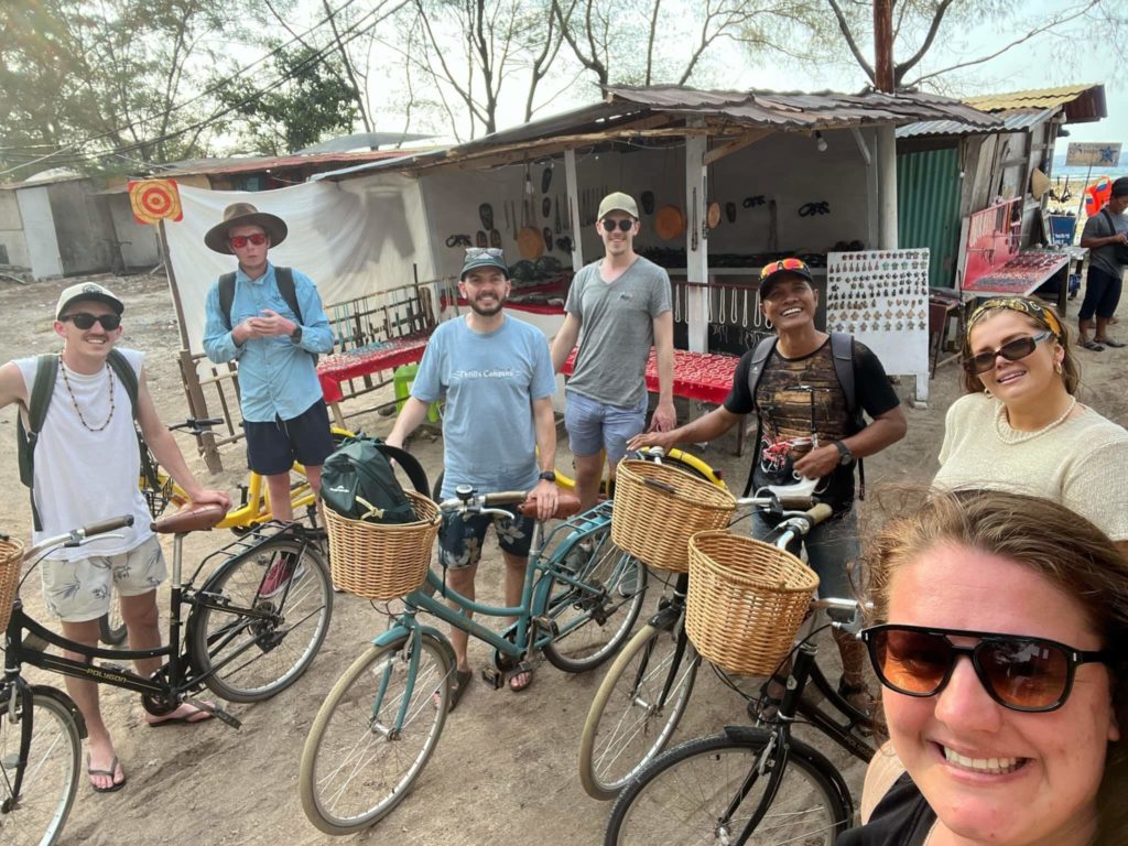 Small group of travellers with bicycles all smiling at camera
