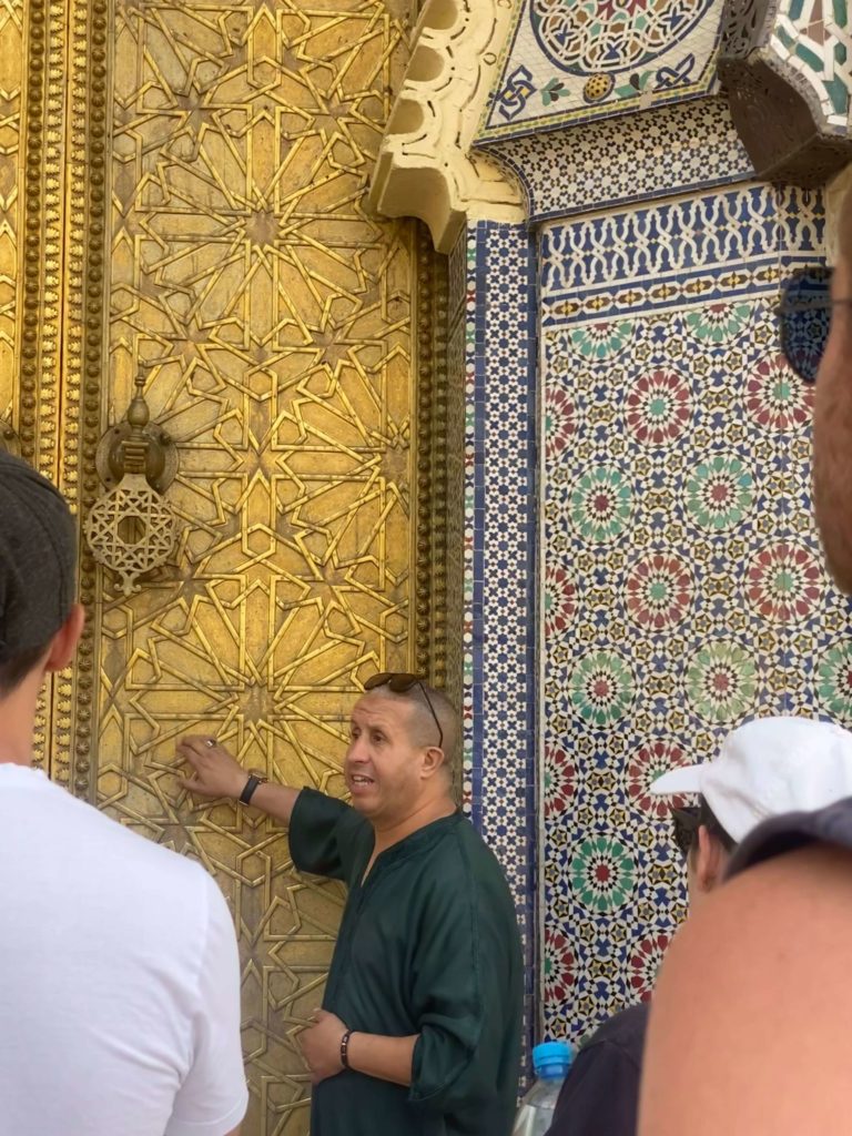 Local man showing group of tourists a golden door with beautiful pattern on it