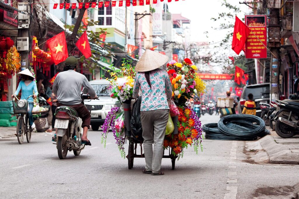 Vietnamese vendor walking through Hanoi street 