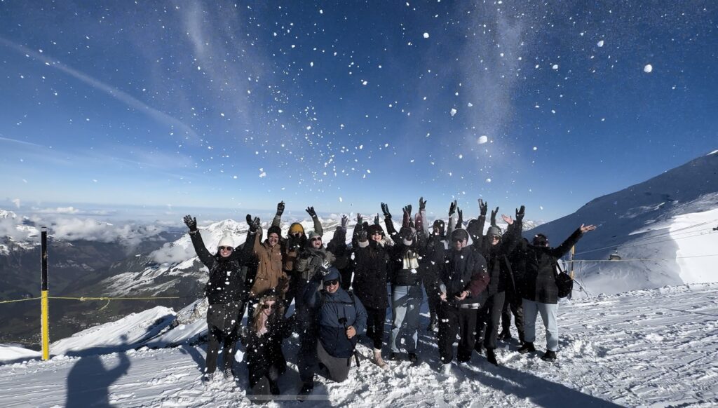 Group posing on top of a snowy mountain 