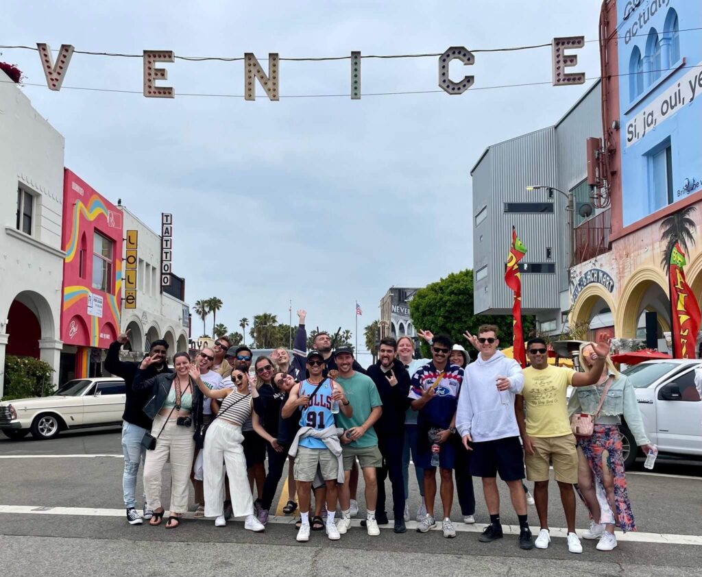 Group of travellers aged 18-24 under Venice sign in LA