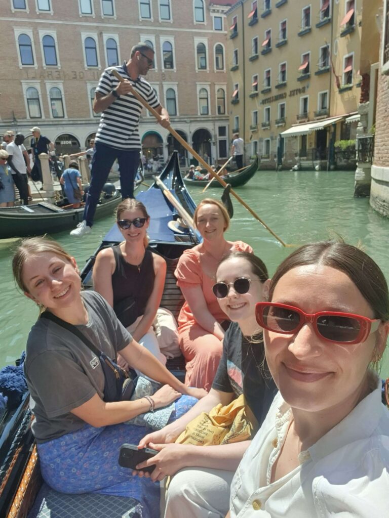 Group of young women taking a selfie on a gondola in Venice.