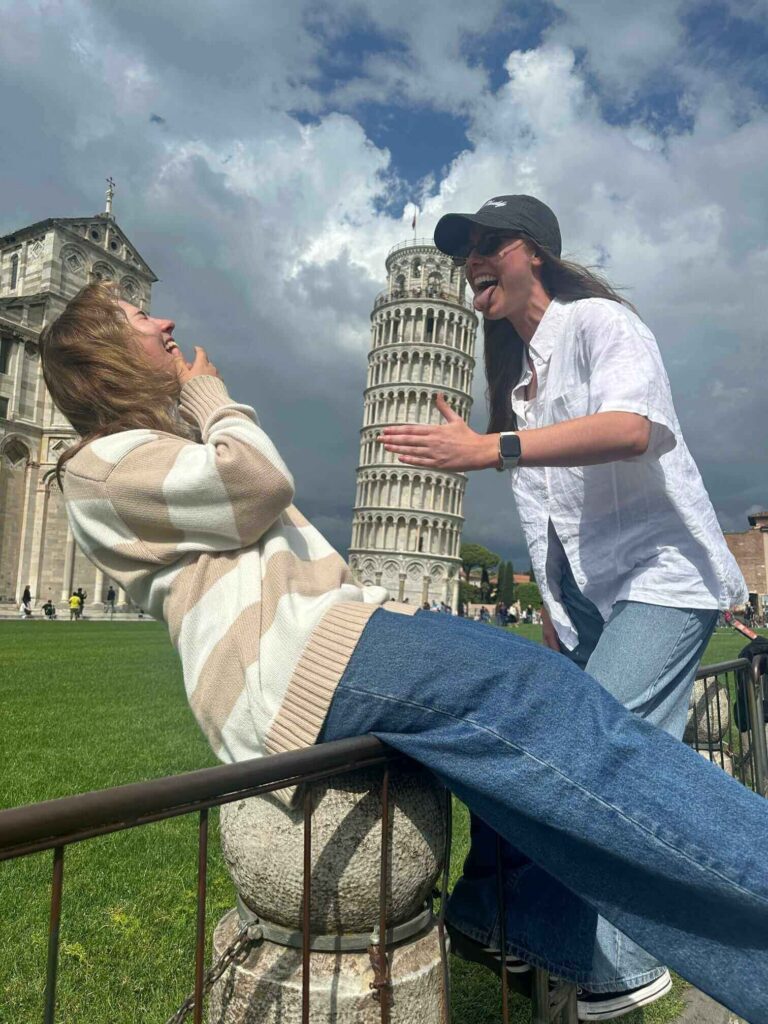 Two travellers laughing by the Leaning Tower of Pisa in Italy on a Topdeck Get Social: Mega European tour.