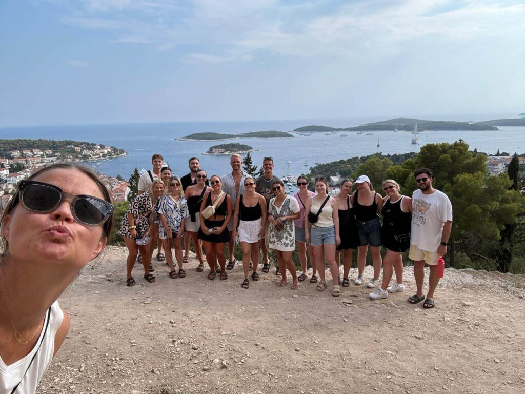 Group of travellers smiling in Croatia with a view of the islands behind